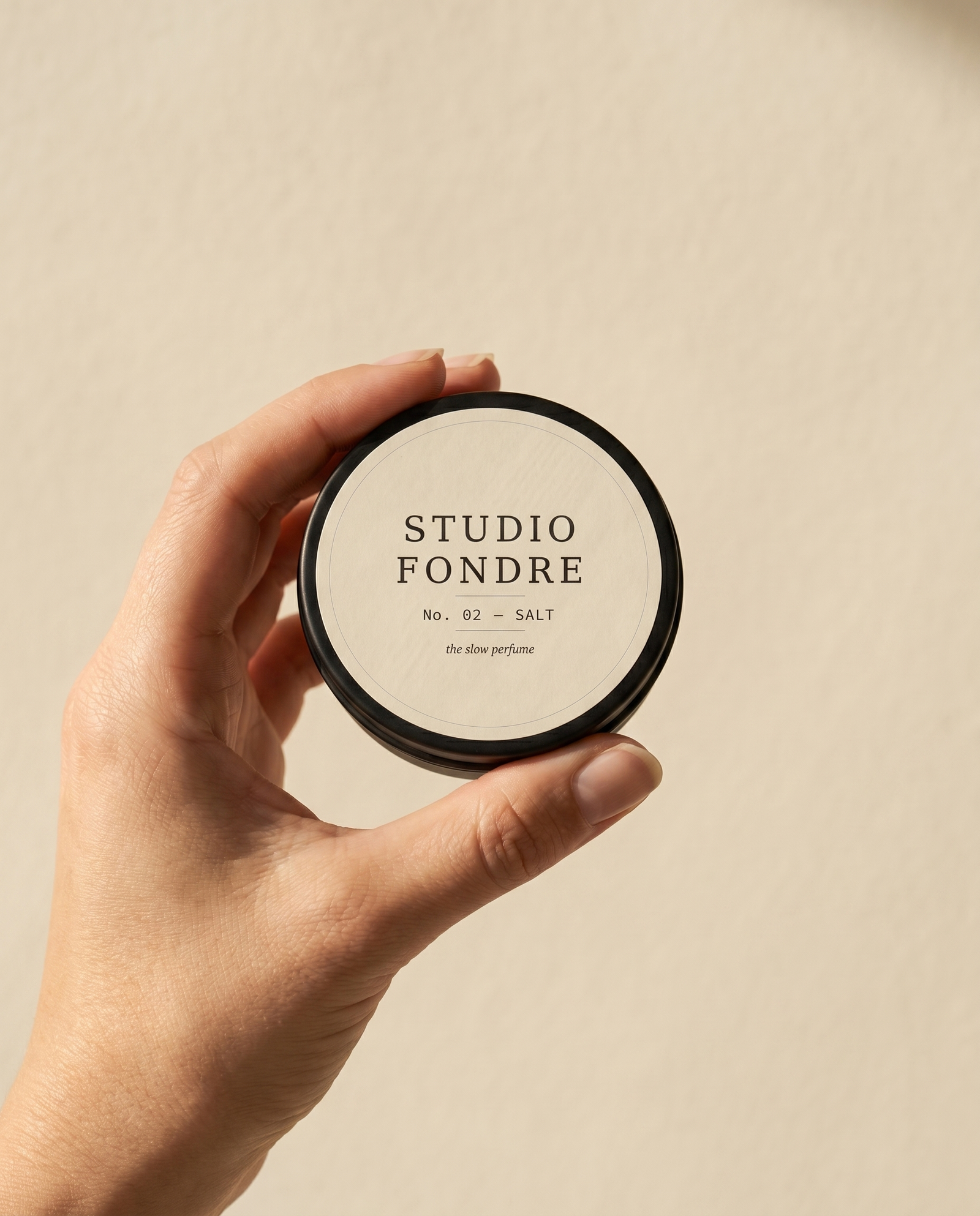 Solid perfume tin held between fingers, showing pocket-sized scale