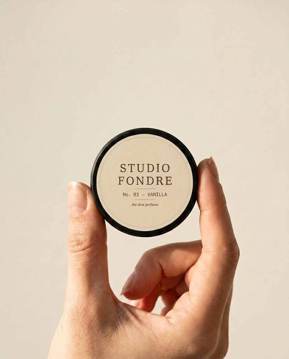 Solid perfume tin held between fingers, showing pocket-sized scale